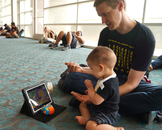  Caption: Brian Felgar finds a quiet spot in the Convention Center to entertain Avery, 11 months, with cereal and video games.
